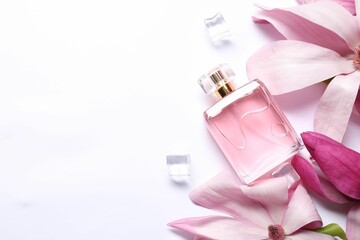 Beautiful pink magnolia flowers, bottle of perfume and ice cubes on white background, flat lay. Space for text