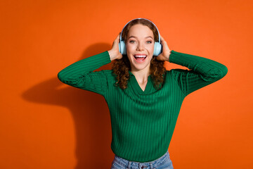 Photo of impressed funky lady dressed green shirt singing listening music earphones isolated orange color background