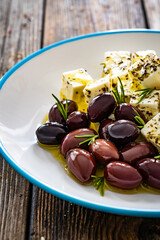 Greek style salad - feta cheese and kalamata olives on wooden table
