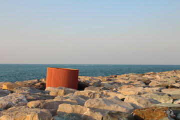 A red container on rocks by the water