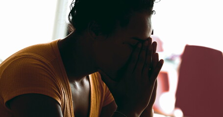 Young African American woman struggles with depression at home in quiet despair feeling overwhelmed...