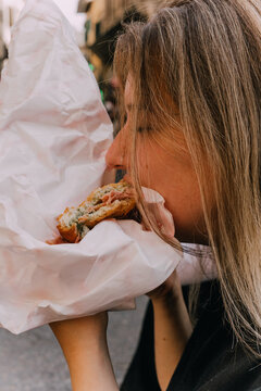 Young woman taking a big bite of panini sandwich ugc