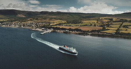 Scotland, Brodick Ferry Terminus aerial panoramic shot of ship crossing, Arran Island. Beautiful passenger ferry go from harbor at Firth-of-Clyde Gulf to mainland. Cinematic scenery view