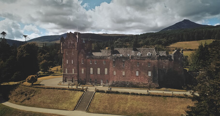 Scotland Brodick Castle aerial front shot: heritage of Scottish. Historical landmark of Arran Island with majestic landscape. Parks and garden near building under cloudy sky. Scenery view