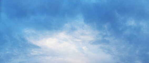 The sky covered with thick blue clouds with a gleam in the middle