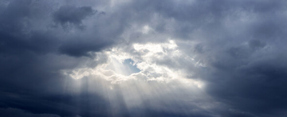Sun rays penetrate through dark storm clouds