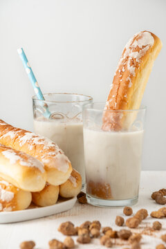 View of glasses of horchata with fartons on table with chufas, white background, vertical