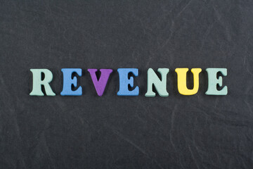 REVENUE word on black board background composed from colorful abc alphabet block wooden letters,...