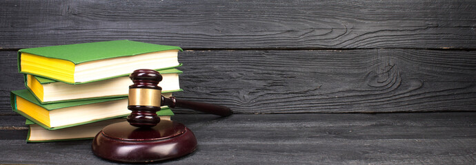 Law concept - Open law book with a wooden judges gavel on table in a courtroom or law enforcement...