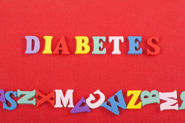 DIABETETES word on red background composed from colorful abc alphabet block wooden letters, copy...