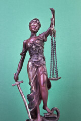 Statue of justice on a green background. Law concept. Copy space for ad text.