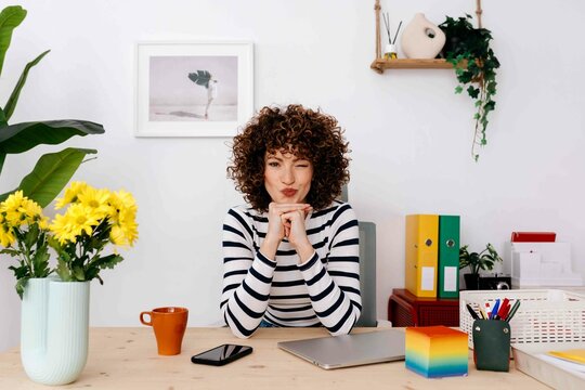 Young woman sitting on chair making funny face in modern office