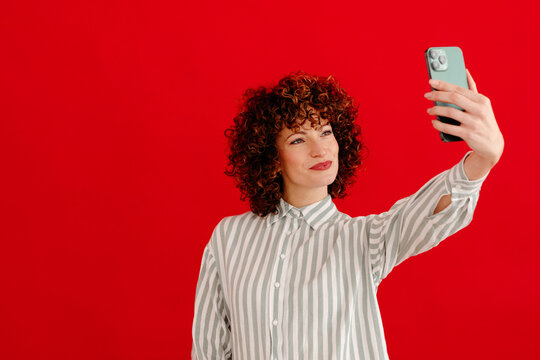 Content woman in stylish outfit taking selfie with smartphone