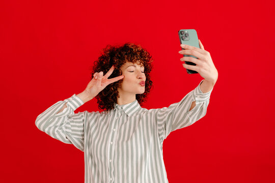 Cheerful woman taking photo of self with smartphone