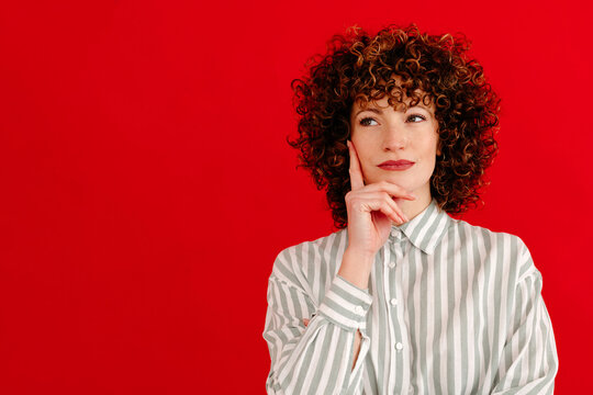 Thoughtful young woman touching chin with finger in studio