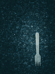 Single White Fork Lying on Dark Asphalt Pavement in Dim Light