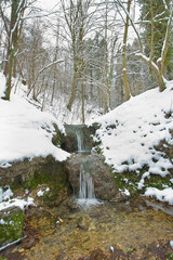 creek and a small waterfall in a winter snow-covered forest. Polish landscape
