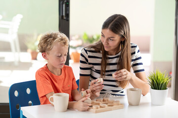 A mother plays at home with her son with a wooden educational toy