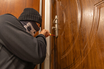 Burglary, a masked thief in a balaclava opens the door