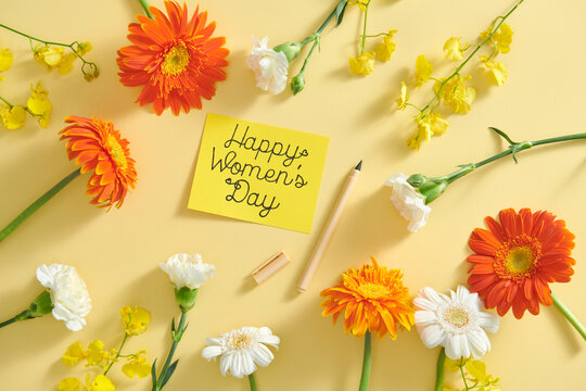 Happy Women's day text on a craft card and beautiful flowers