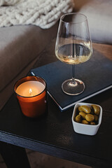 Burning candle, glass of white wine and olives on the table