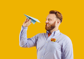 Portrait of a young bearded redhead happy man tourist throwing paper plane planning summer holiday...