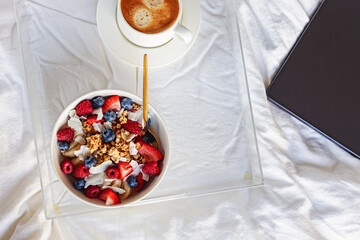 Breakfast with yogurt granola bowl topped with berries and coffee, view from the top