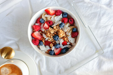 Breakfast yogurt and granola bowl topped with berries and coconut chips, top view