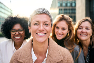Portrait group of multiracial empowered business women of diverse ages looking smiling at camera...