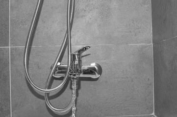 Chrome shower faucet with flowing water in a bathroom