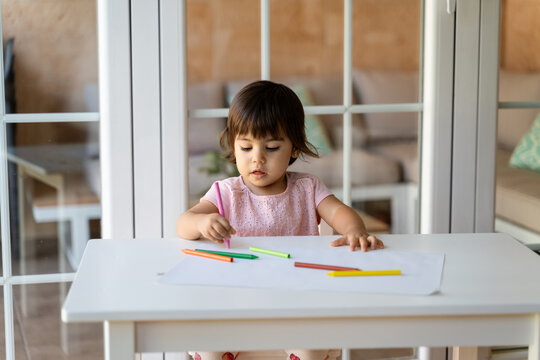 girl drawing with colored pencils at table in living room
