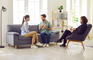 Working on relationships. Psychologist listens to conversation of married couple during therapy session. Couple sits on sofa and resolves conflict in therapy session. Concept of marital therapy. - obrazy, fototapety, plakaty