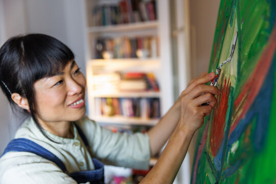 Smiling painter painting on canvas with palette knife