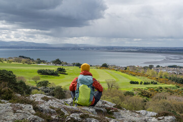 Dublin Bay and North Bull Island. Hiker man admires Irish landscape from Howth mountains.