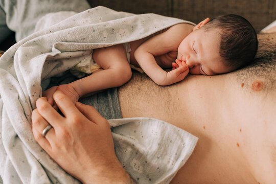 Newborn baby sleeping on father's belly