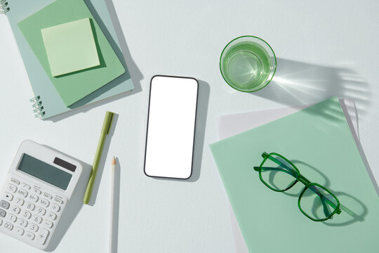 Office table with a blank screen smartphone. View from above