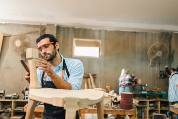 Diligently skilled man work with wood in carpenter's shop, using tools and equipment to transform...
