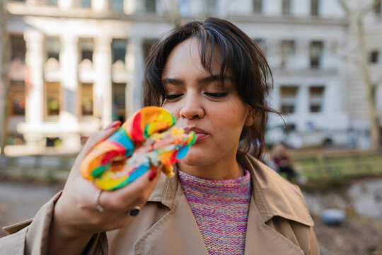 Hispanic woman eating a colorful bagel.