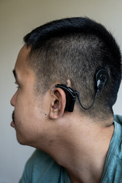 Vertical side profile portrait of a Gen Z guy with a cochlear implant