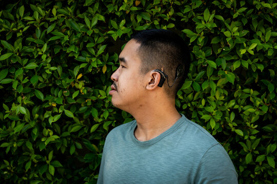 Side profile portrait of a Gen Z guy with a cochlear implant outdoors