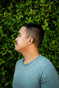 Vertical side portrait of a Gen Z guy with a cochlear implant outdoors