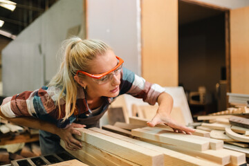 In a bustling carpenter's shop, a young woman craftsman expertly navigates her workshop, merging...