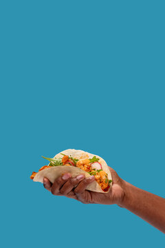Hand holding shrimp taco with copy space.