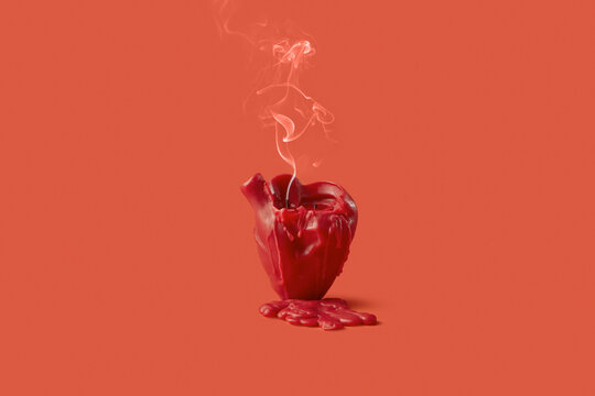 Blown out candle in shape of heart leaving drops of wax in red studio