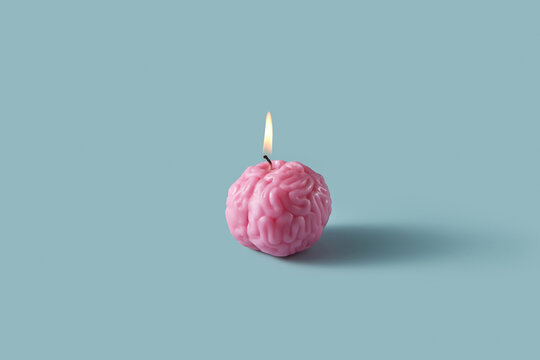 Pink brain-shaped candle burning brightly on grey background