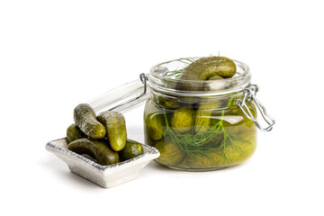 A glass home canning jar of baby dill pickles with the lid partly open isolated on white
