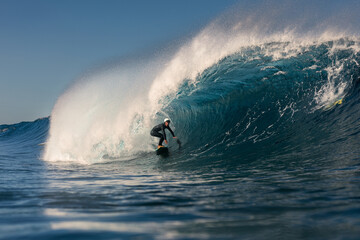 A young surfer has fun while riding a giant wave