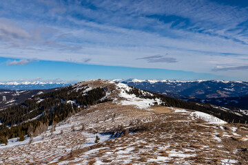 Snow covered alpine meadow with scenic view of Karawanks and Lavanttal Alps, Carinthia, Austria....