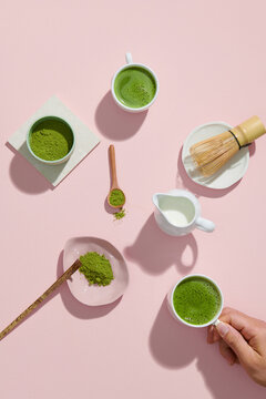 Matcha latte in a cup, powder and tools for making tea on green table
