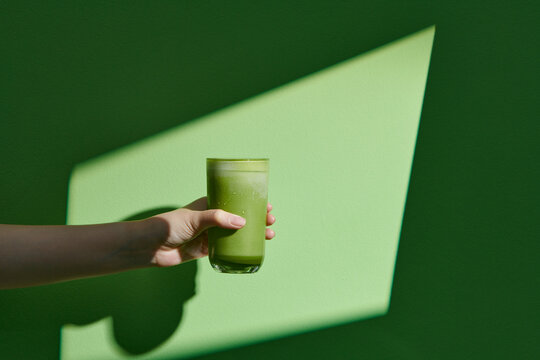 hand holding iced matcha latte green tea cup